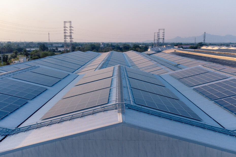 Future green energy and sustainable electricity resource concept. Outdoor focus on solar panels on rooftops or photovoltaics of factories by drone. Industrial roof with solar cell grid with blue tone.