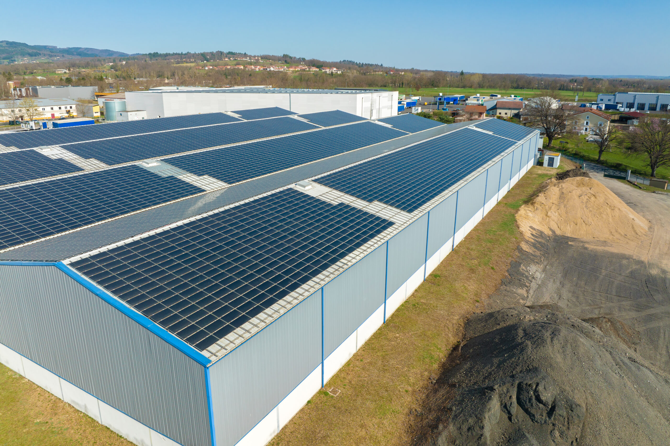 Aerial view of solar power plant with blue photovoltaic panels mounted on industrial building roof for producing green ecological electricity