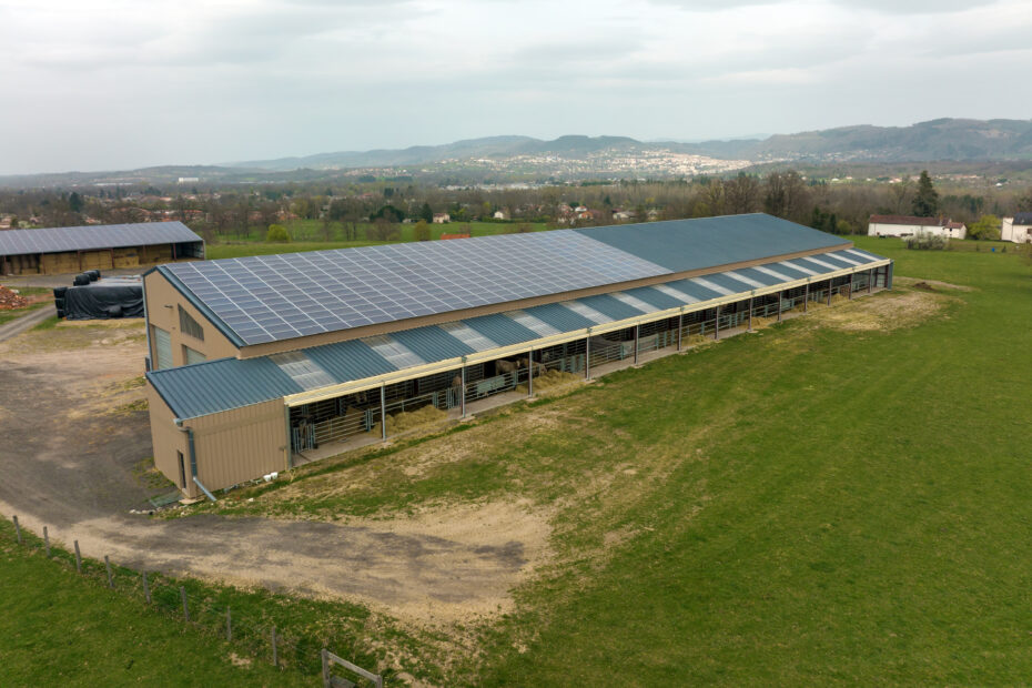 Aerial view of farm building with photovoltaic solar panels mounted on rooftop for producing clean ecological electricity. Production of renewable energy concept.