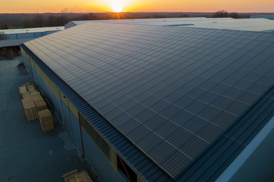 Aerial view of blue photovoltaic solar panels mounted on industrial building roof for producing green ecological electricity. Production of sustainable energy concept.